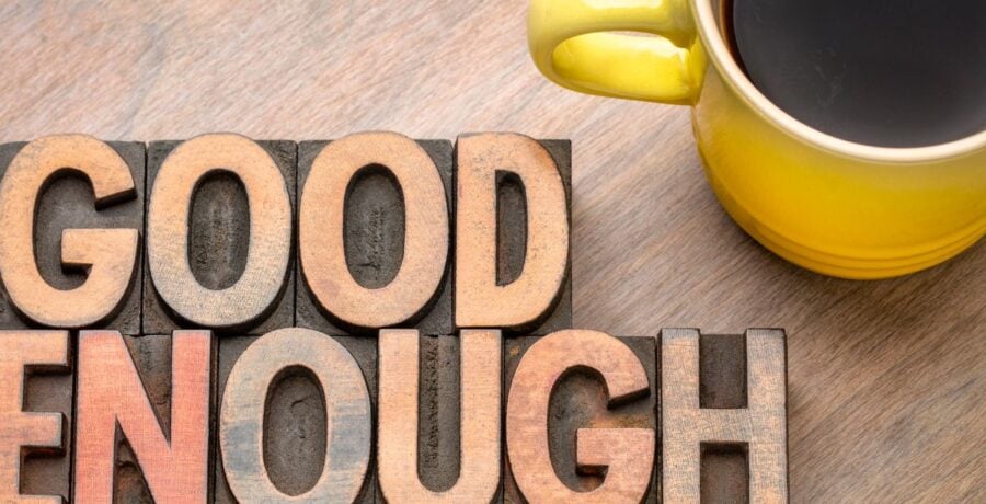Good enough in wooden words, with a yellow mug by the side