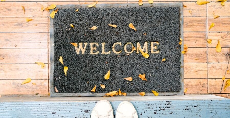 Welcome Mat With Feet Next To It Waiting To Come In